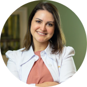 Imagem da Dermatologista Elisa Q. Coelho. Mulher branca de cabelos curstos e claros, usa um jaleco branco sobre uma blusa rosa.